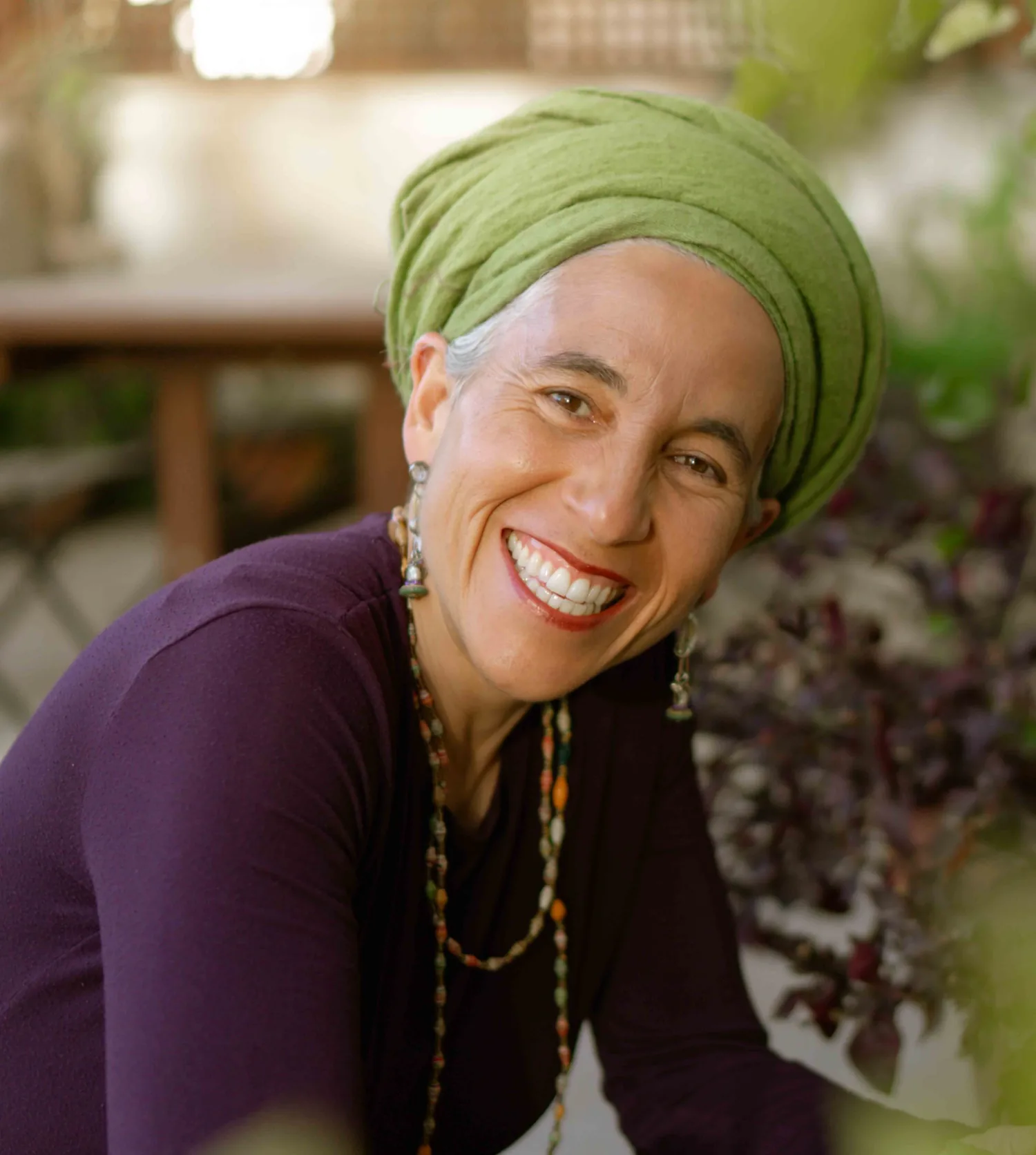 Chana Mason leaning in, laughing, in a green head wrap